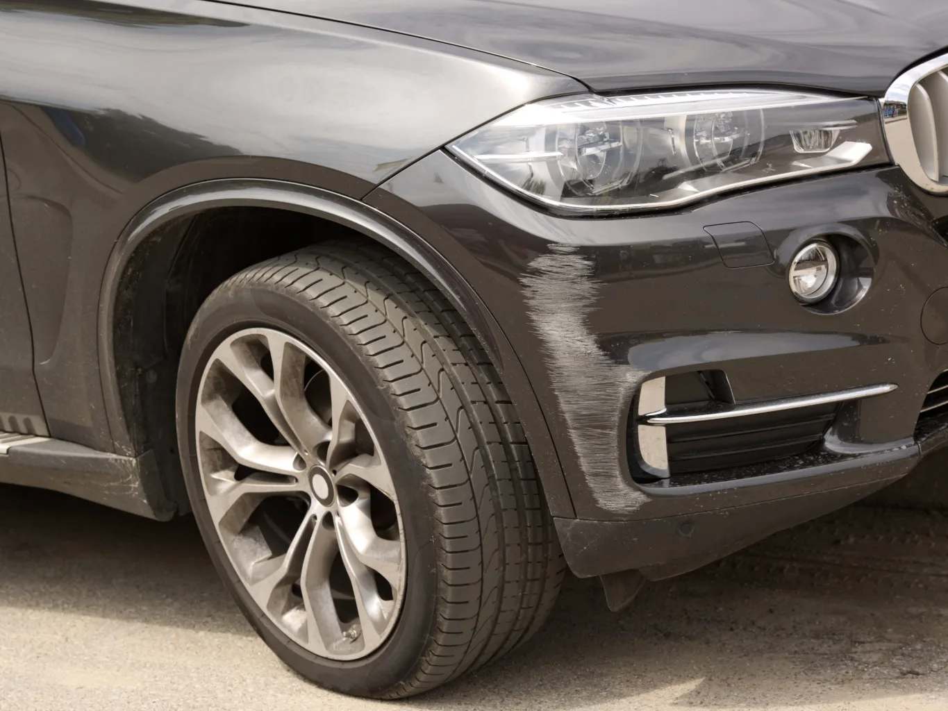 During the disassembly stage of a bumper repair, an auto body technician uses a plastic trim removal tool to release fasteners along the edge of a vehicle's bumper cover